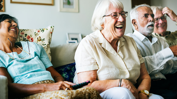 Four elderly people sitting on a couch laughing